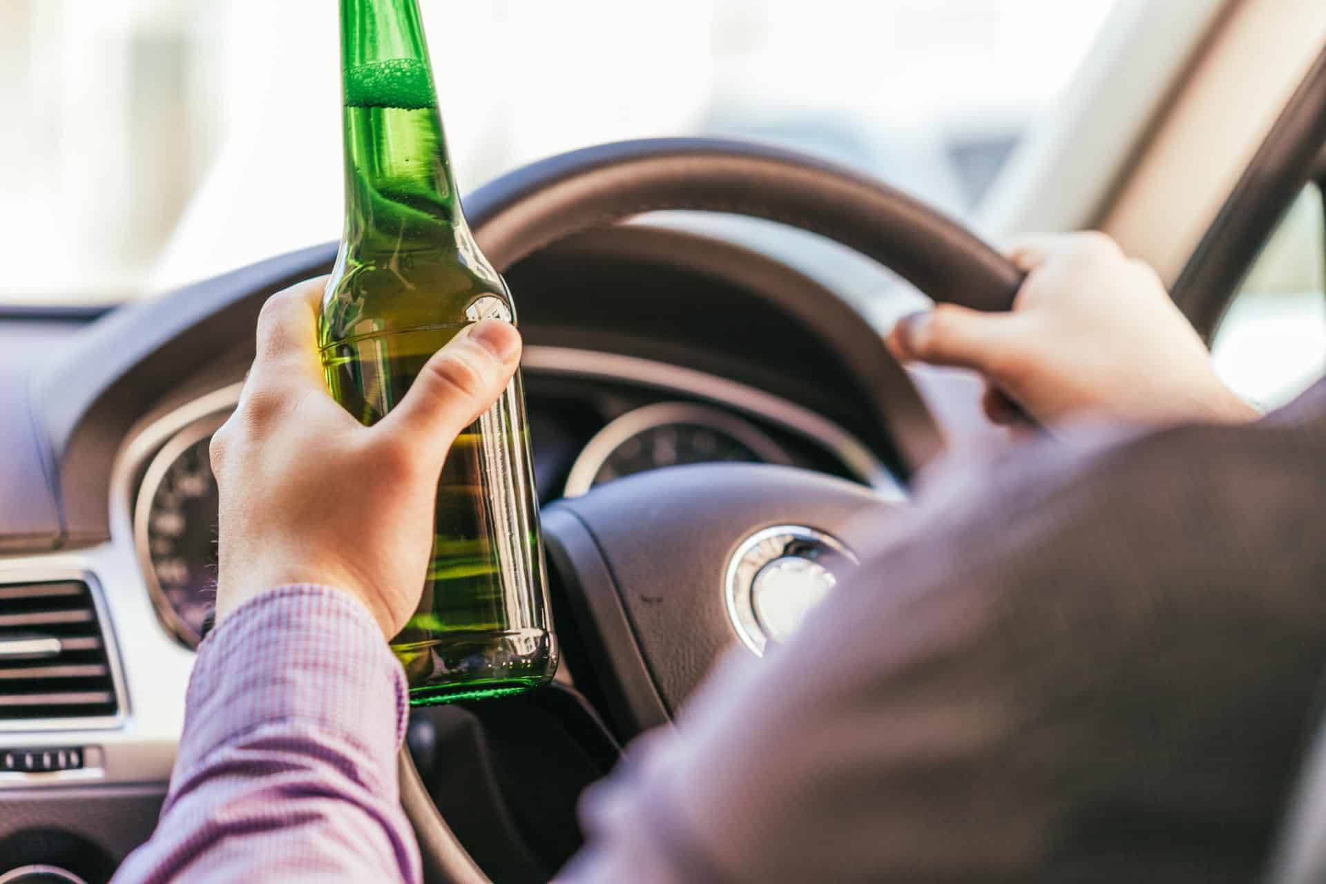 Man drinking a beer while driving a car.