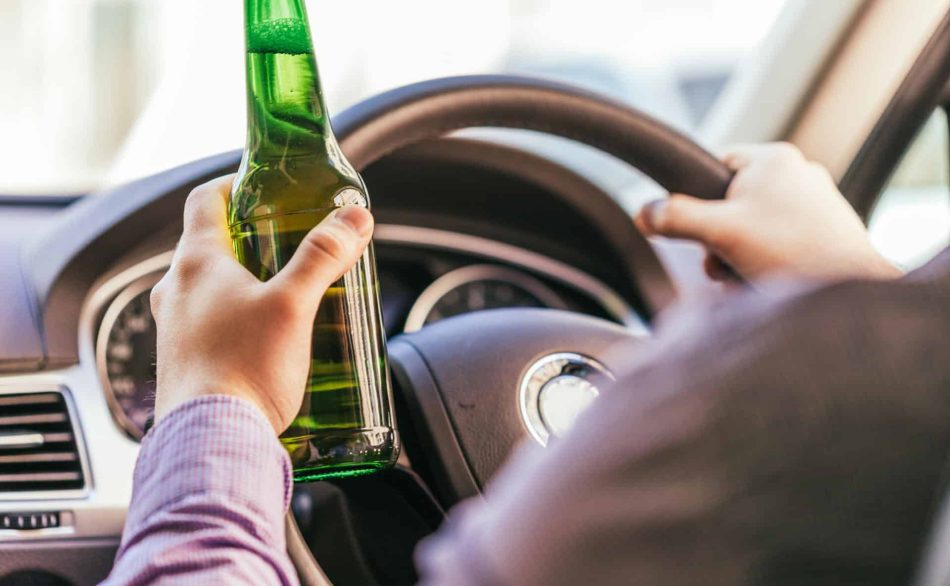 Man drinking a beer while driving a car.